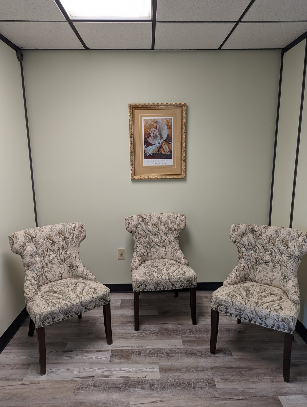 A small counseling room with three patterned chairs.